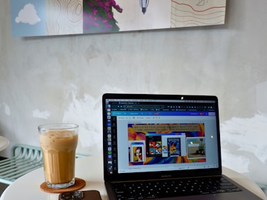 A minimalist workspace with a laptop displaying a clean website layout, surrounded by a coffee cup and notepad.