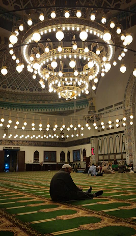 Elegant mosque chandeliers and wall sconces glowing warmly in a prayer hall