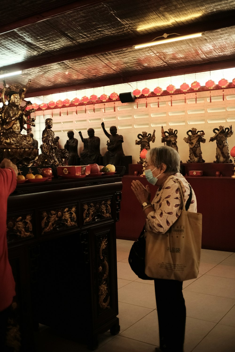 a woman wearing a face mask standing in front of a shrine
