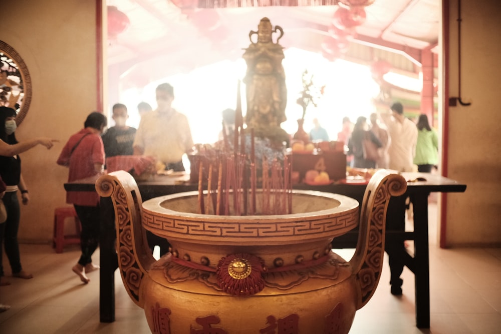 a group of people standing around a table with a vase on it