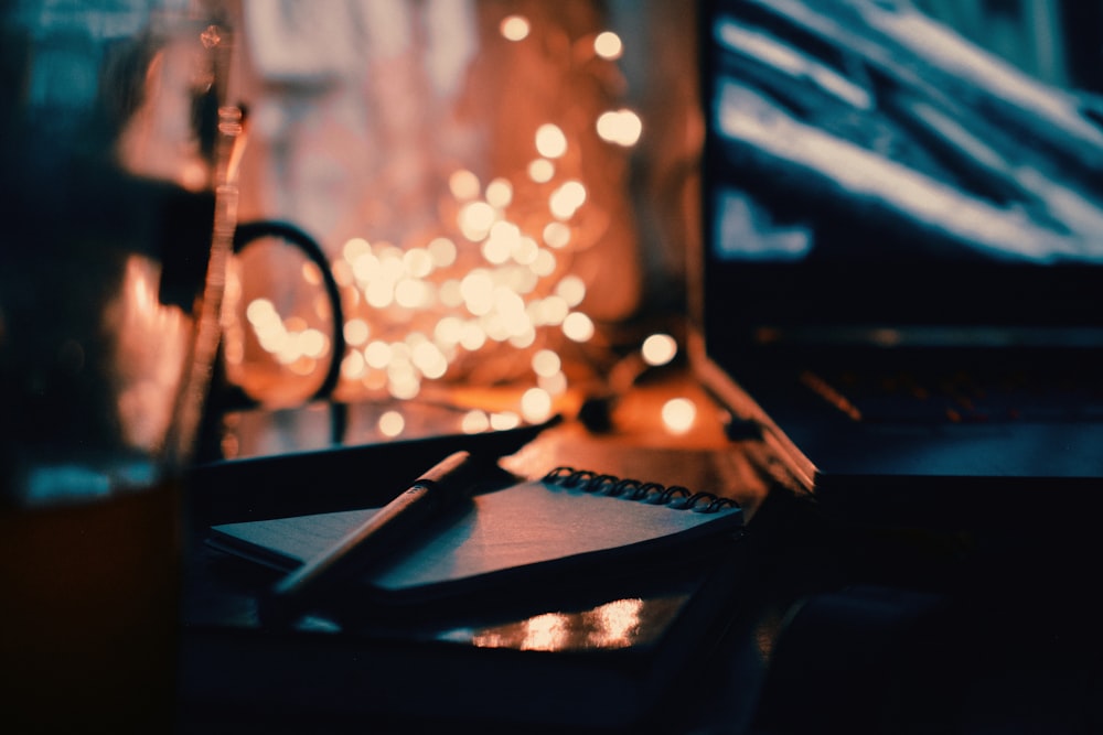 a desk with a pen, notebook and a laptop on it