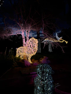 Evening scene with illuminated wooden sculptures glowing softly against the dark sky