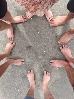 A circle of people standing barefoot on grass, holding hands under a starry night sky.