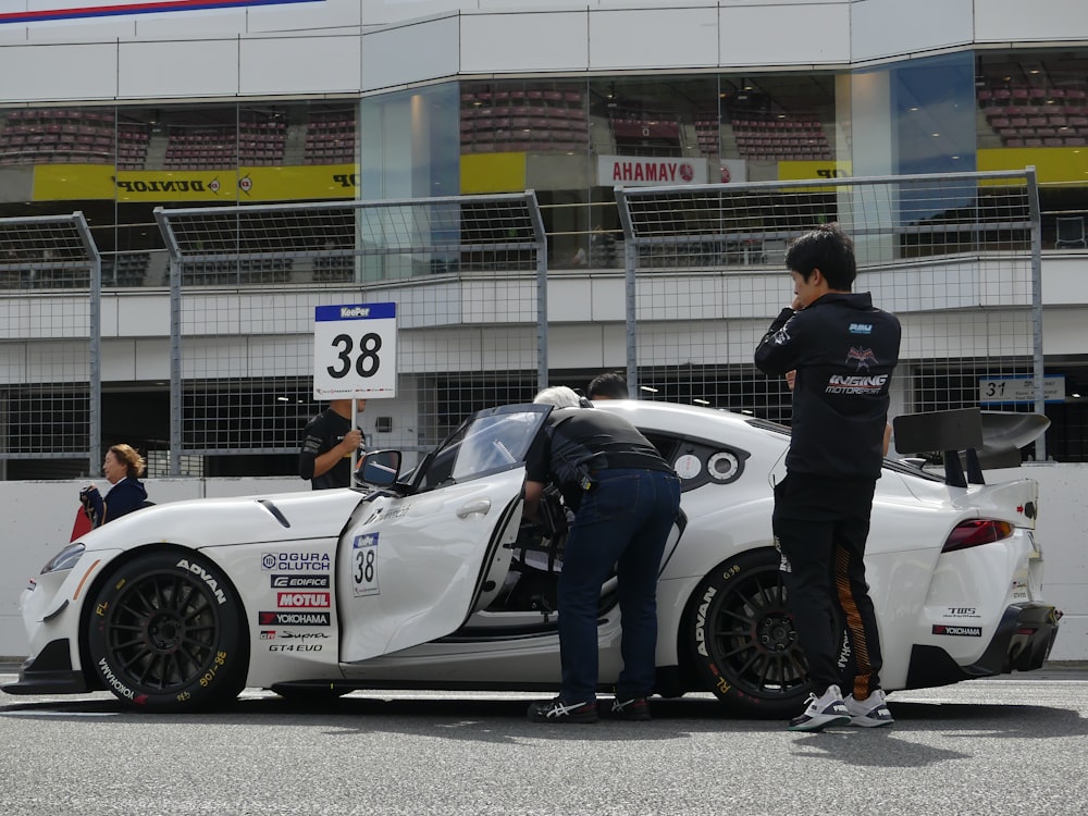 a man standing next to a white sports car