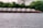 A barge loaded with piles of gravel is floating on a river, with a backdrop of dense green trees and some industrial buildings. The barge is labeled with the words 'Material Service' and the number 'MSC9802'.