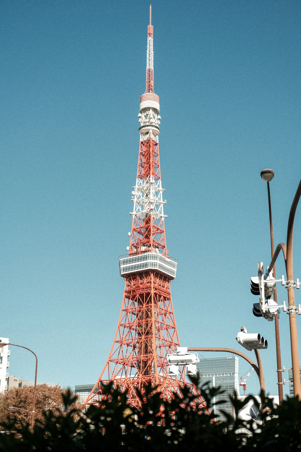 uma torre vermelha e branca muito alta elevando-se sobre uma cidade