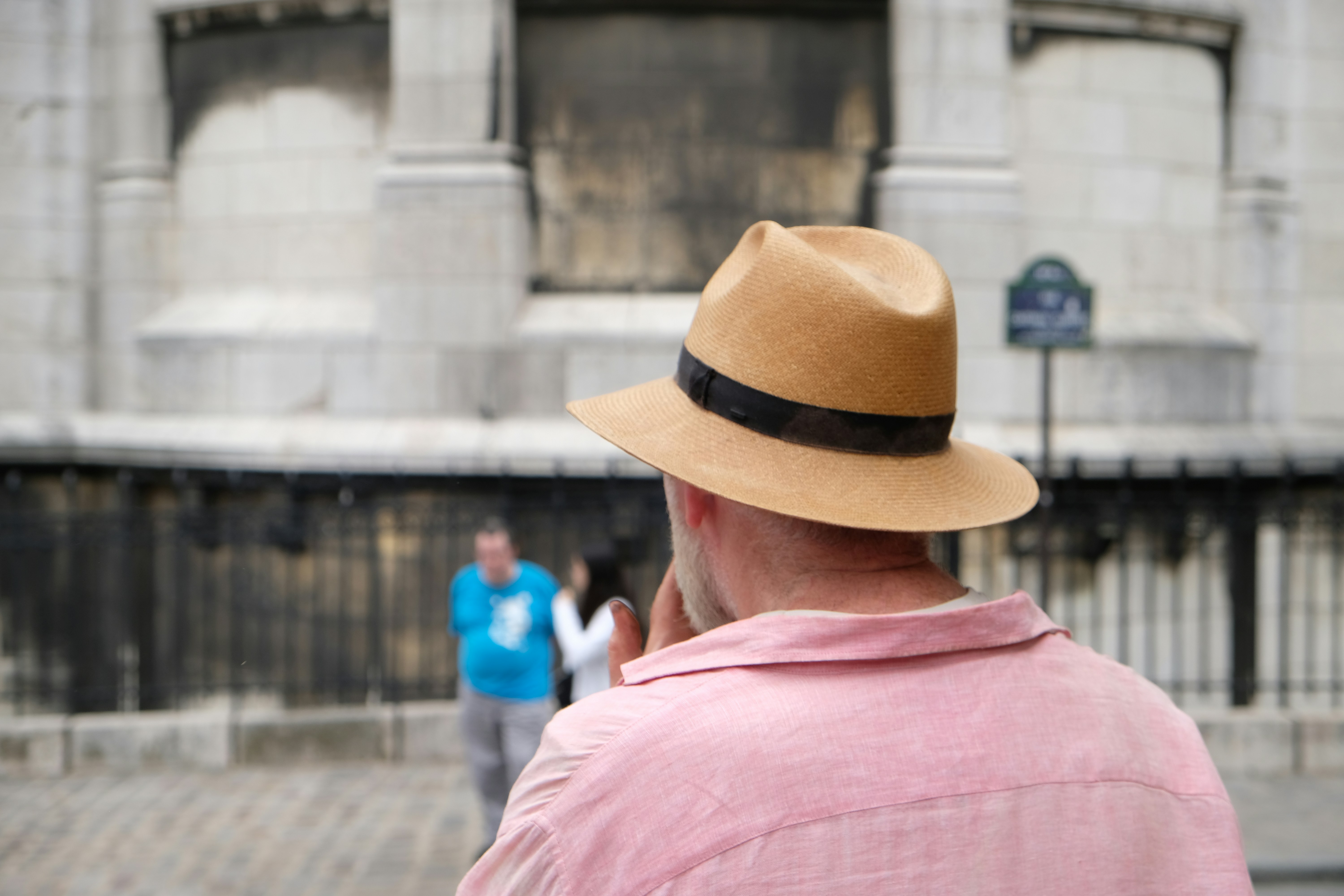 a man wearing a hat standing in front of a building