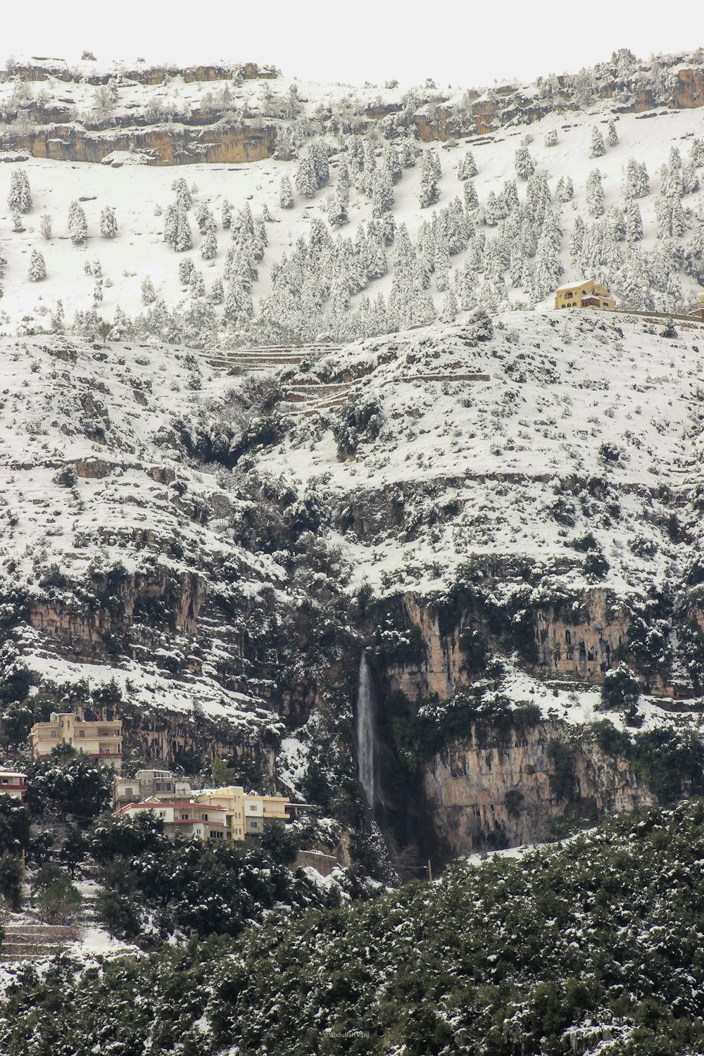 a snow covered mountain with a small waterfall