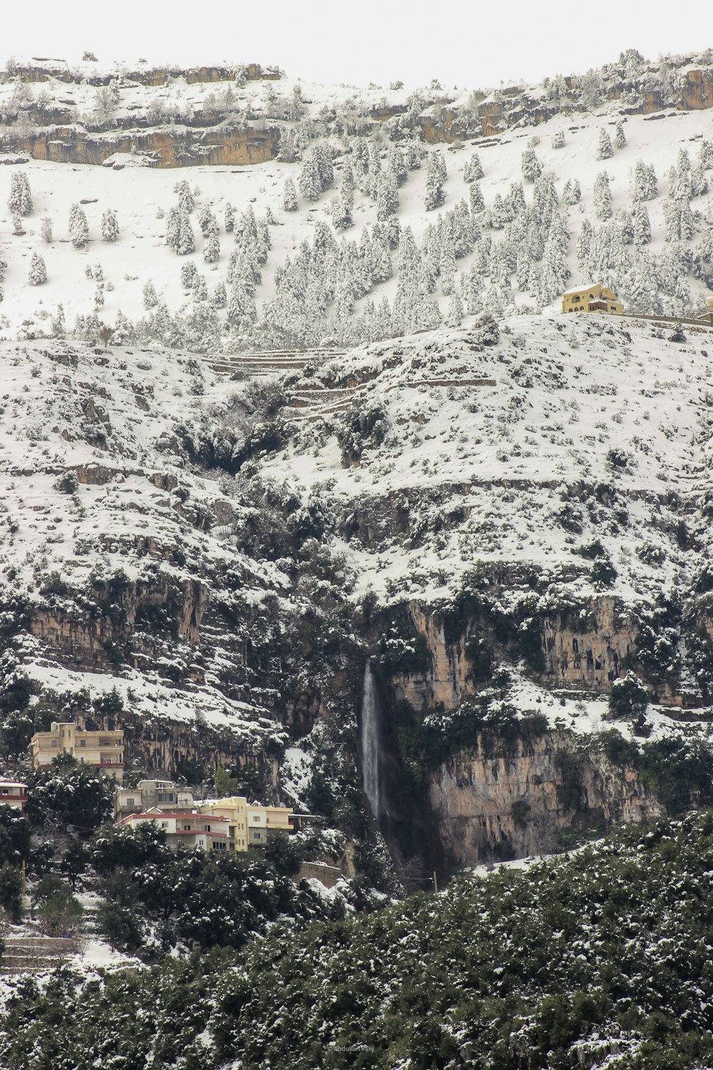 una montaña cubierta de nieve con una pequeña cascada