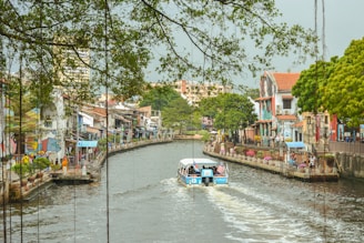 a boat traveling down a river next to tall buildings