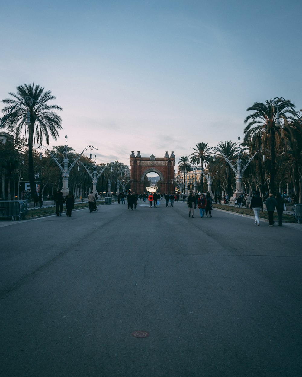 a group of people walking down a street next to palm trees