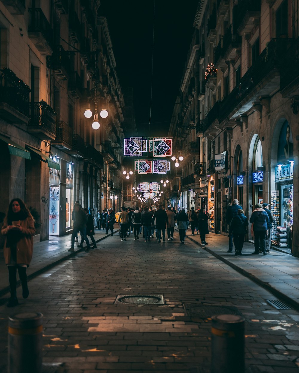 a group of people walking down a street at night