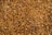A dense layer of small wood chips covering the ground. The chips vary in size and shape, creating a textured surface. The colors range from light tan to rich brown with some darker pieces interspersed, giving the image a natural, organic look.