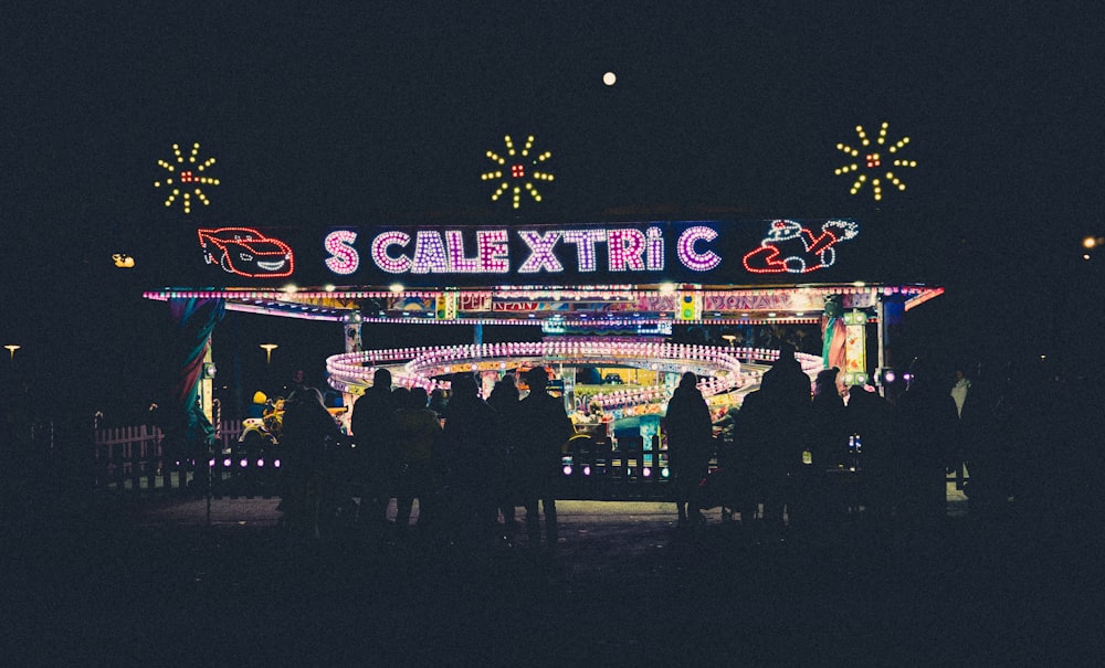 people standing in front of a carnival at night