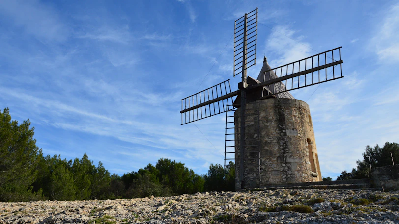 an old windmill on a rocky hillside under a blue sky