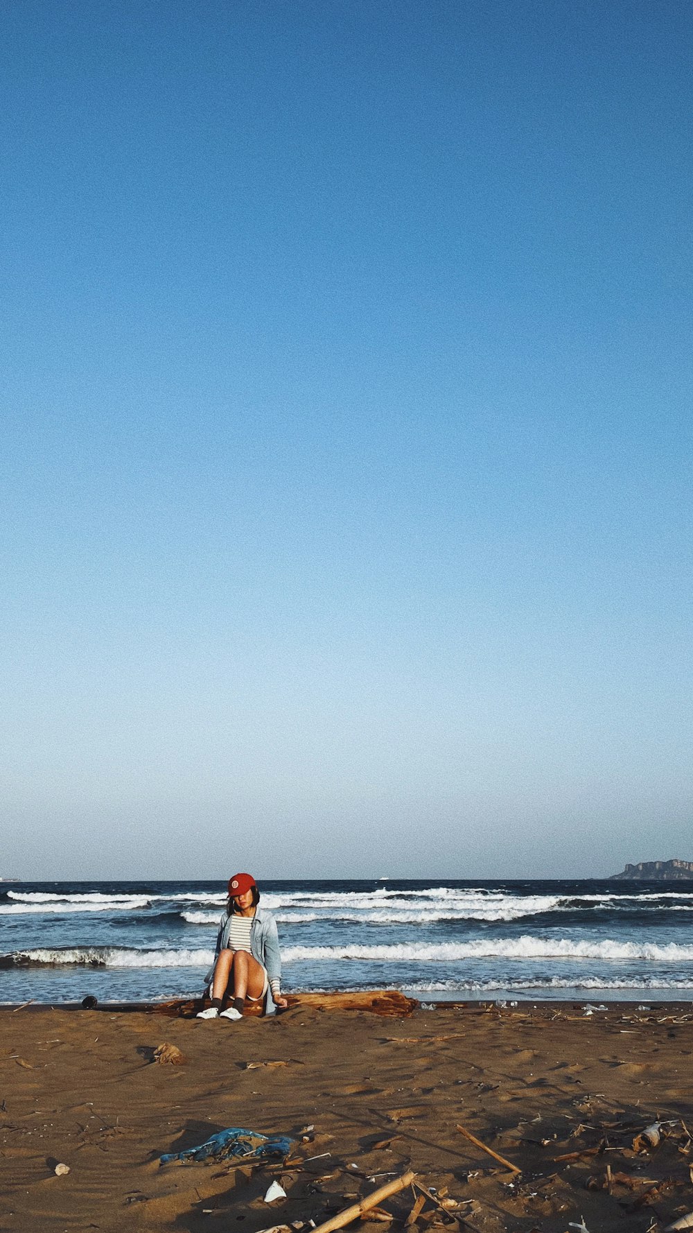 a woman sitting on a beach next to the ocean