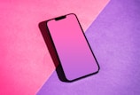 a pink and purple phone sitting on top of a purple and pink background