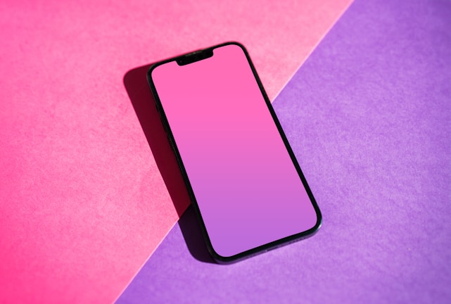 a pink and purple phone sitting on top of a purple and pink background