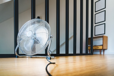 a fan sitting on the floor in front of a stair case