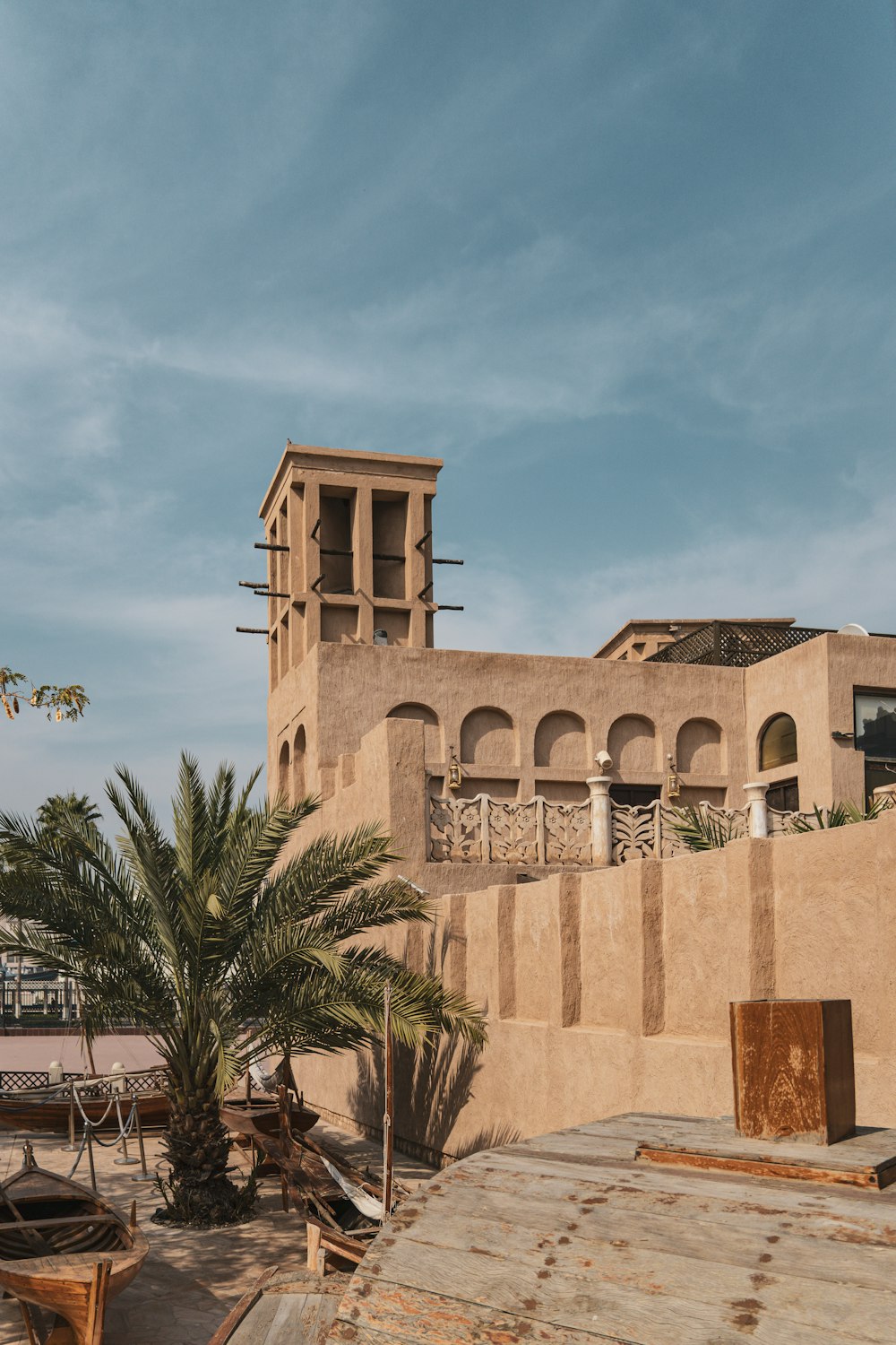 a brown building with a clock tower next to a palm tree