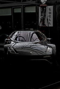 A sleek car with glossy ceramic coating reflecting sunlight, parked in a clean, modern garage.