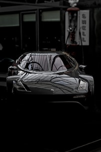 A sleek car being carefully inspected in a modern workshop.