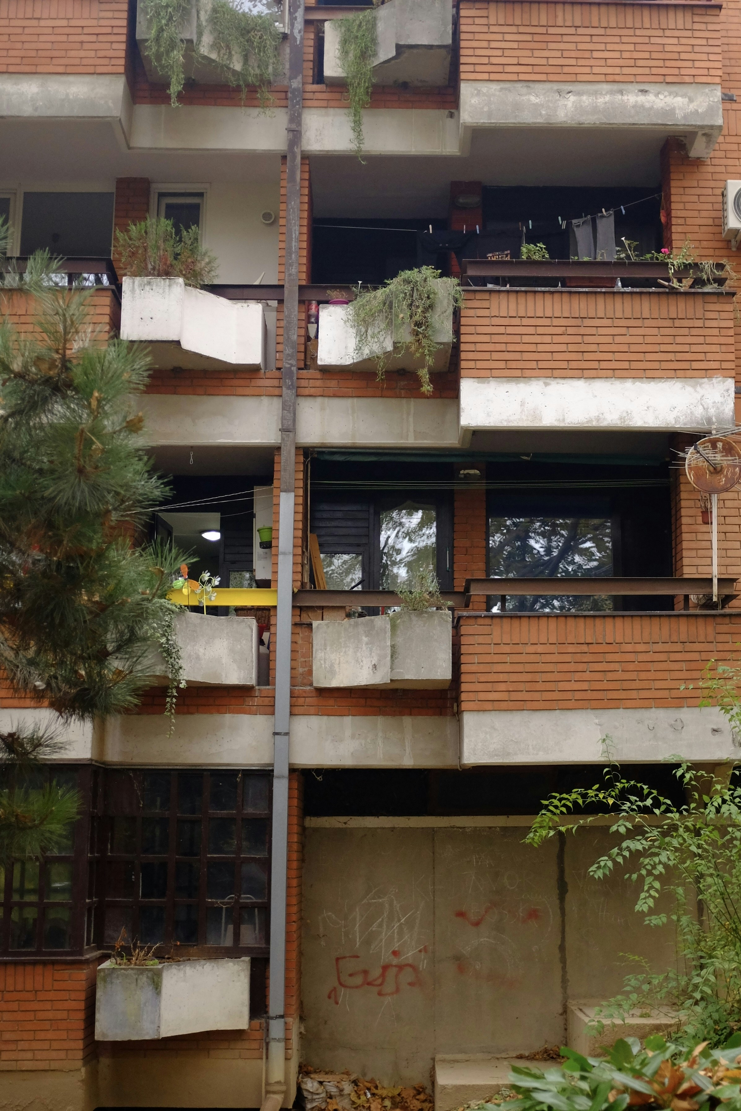 a tall brick building with balconies and plants on the balconies