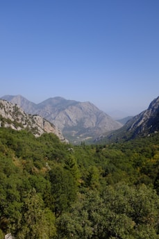 A scenic view of a lush green valley surrounded by mountains, ideal for outdoor activities.