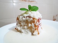 Close-up of a guava jelly dessert topped with a sprig of mint on a white plate