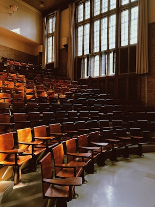 A serene lecture hall with students attentively taking notes, bathed in soft natural light through traditional windows.