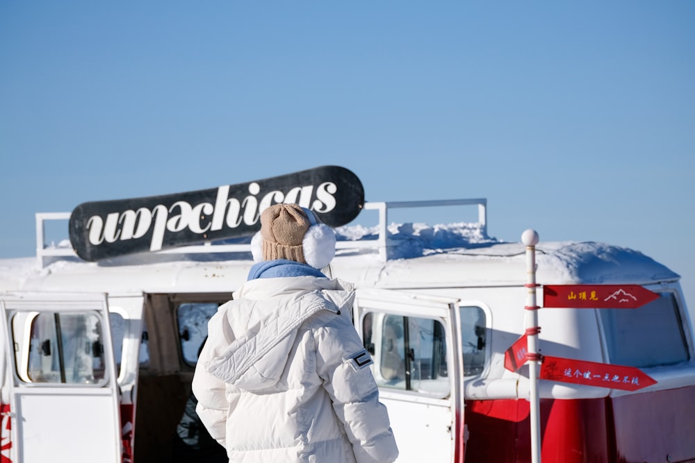 a person standing in front of a bus with a snowboard on top of it