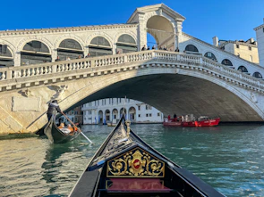 A gondola gliding through Venice's serene canals beneath historic bridges.
