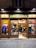 A clothing store display with wooden frames and glass windows showcasing various garments and shoes. Inside, two people are browsing the merchandise. The sign above the entrance reads 'VIA TOLEDO' and the street number 291 appears on both sides of the entrance.