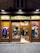 A clothing store display with wooden frames and glass windows showcasing various garments and shoes. Inside, two people are browsing the merchandise. The sign above the entrance reads 'VIA TOLEDO' and the street number 291 appears on both sides of the entrance.