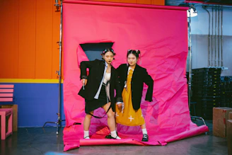 Two models styled in matching streetwear sets leaning against a stark white wall
