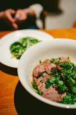 Close-up of a slow-cooked meat dish being carefully packed for delivery.