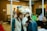 People are gathered in a room, some wearing unique animal hats and holding phones. The setting resembles an office space with glass walls, a whiteboard, and various tech-related decorations on the walls. The group appears to be engaged in a casual and playful activity.