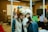 People are gathered in a room, some wearing unique animal hats and holding phones. The setting resembles an office space with glass walls, a whiteboard, and various tech-related decorations on the walls. The group appears to be engaged in a casual and playful activity.