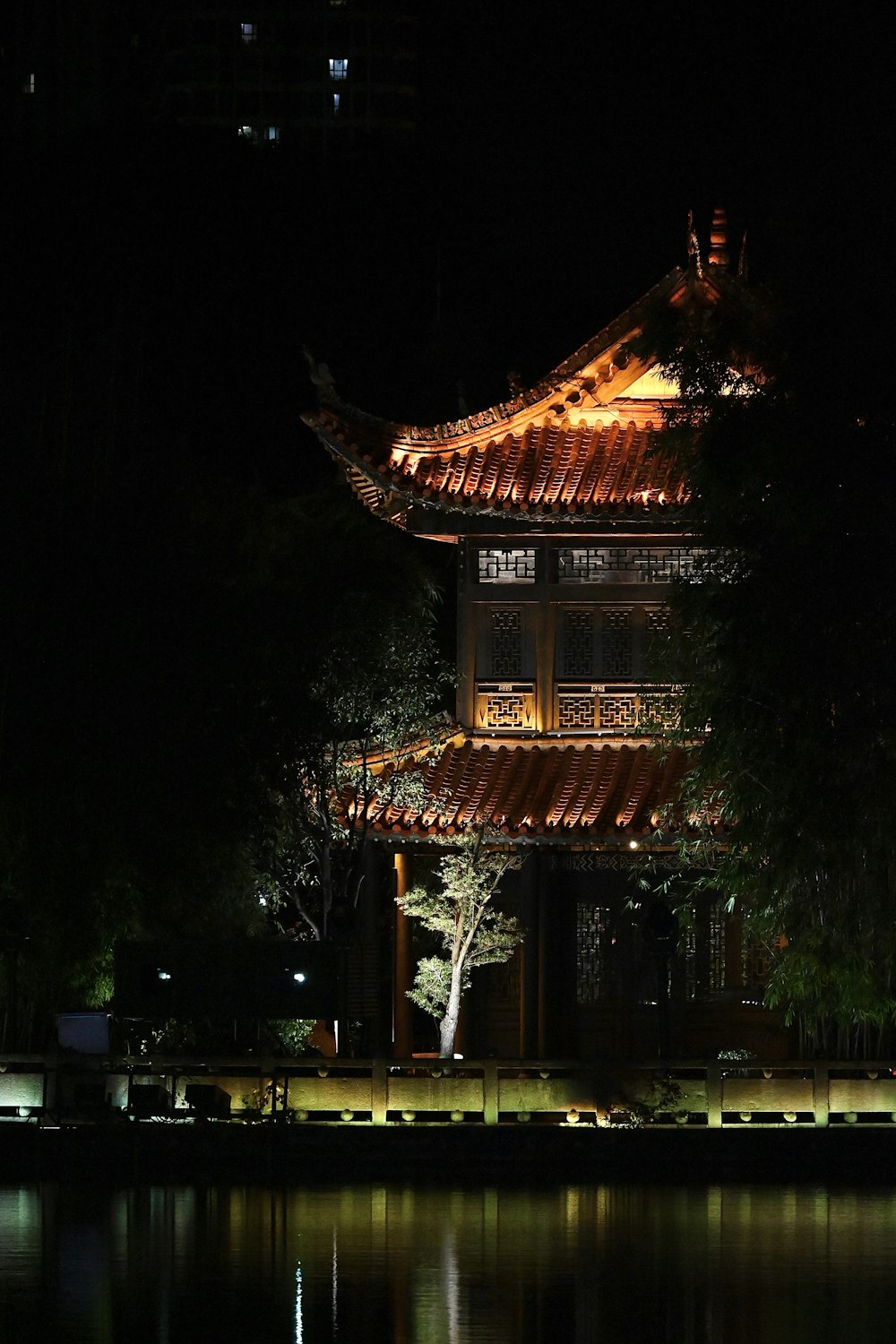 a building lit up at night with lights reflecting in the water