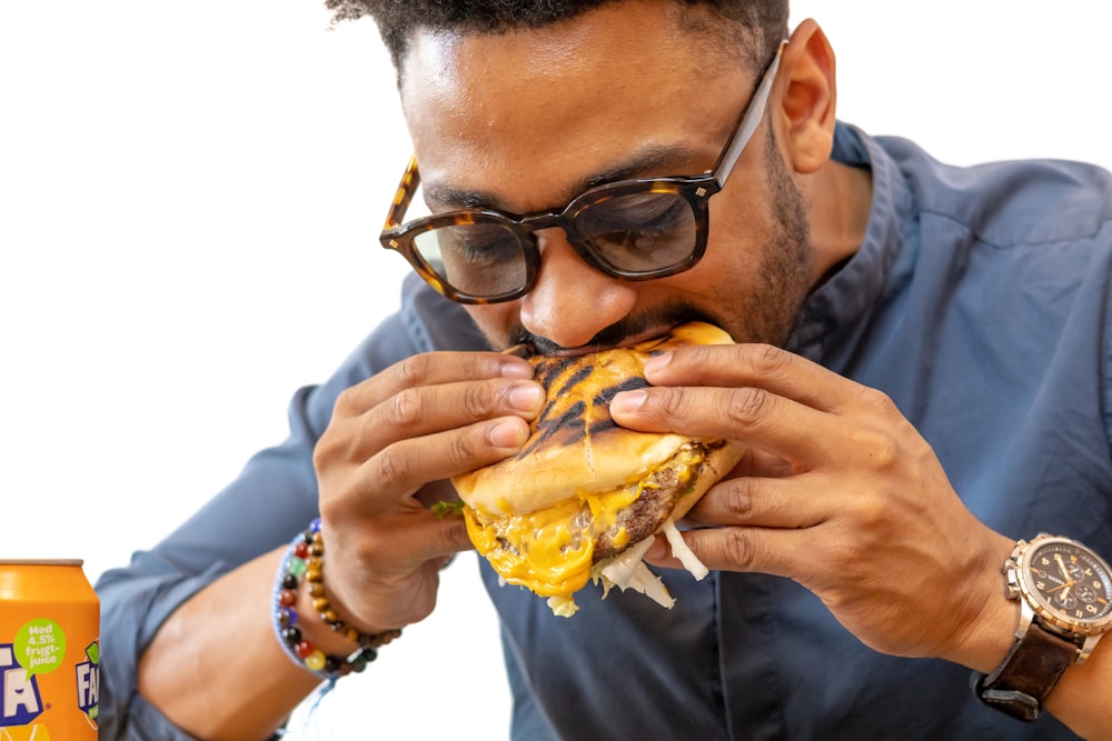 a man in glasses is eating a large sandwich