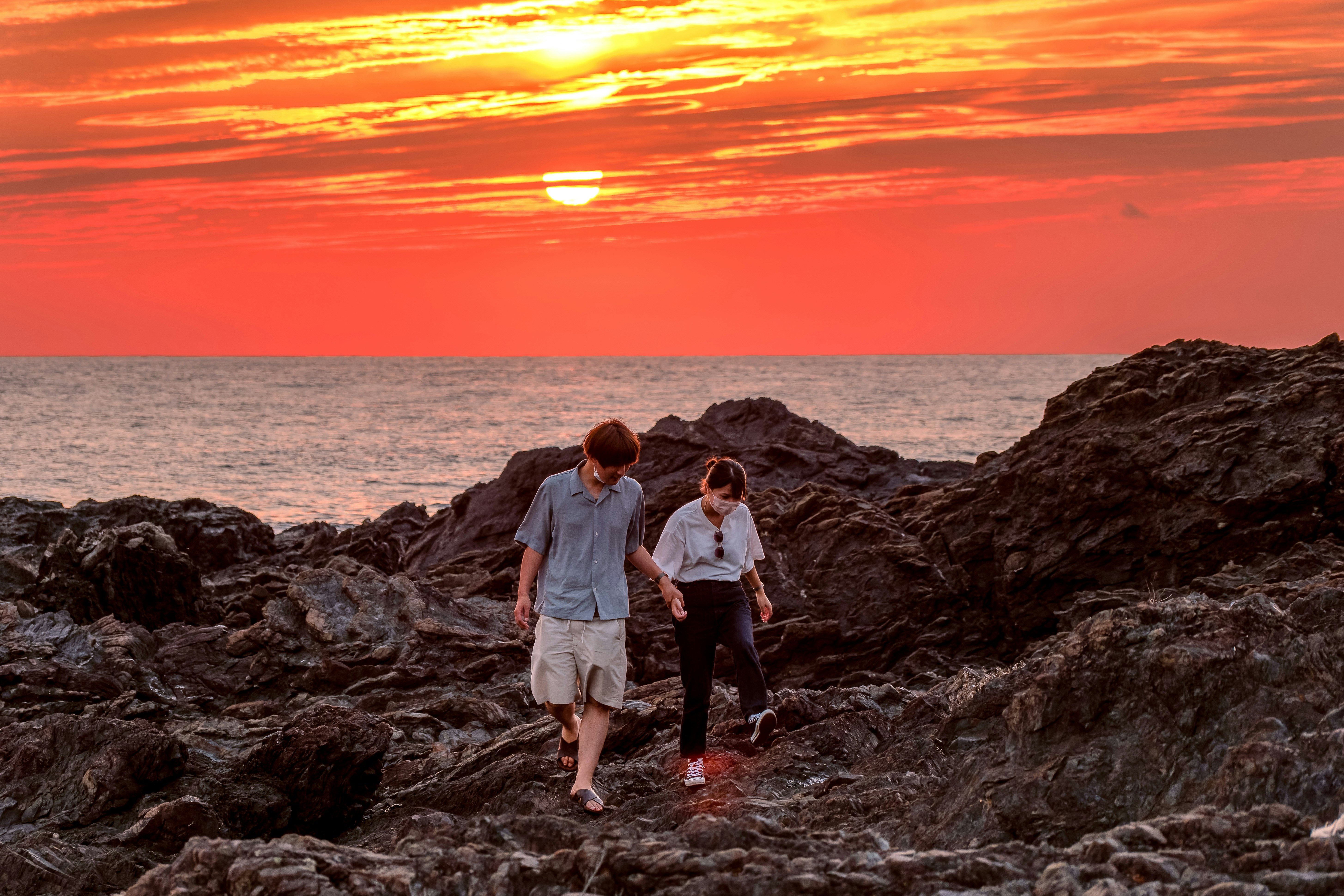 a couple of people standing on top of a rocky beach