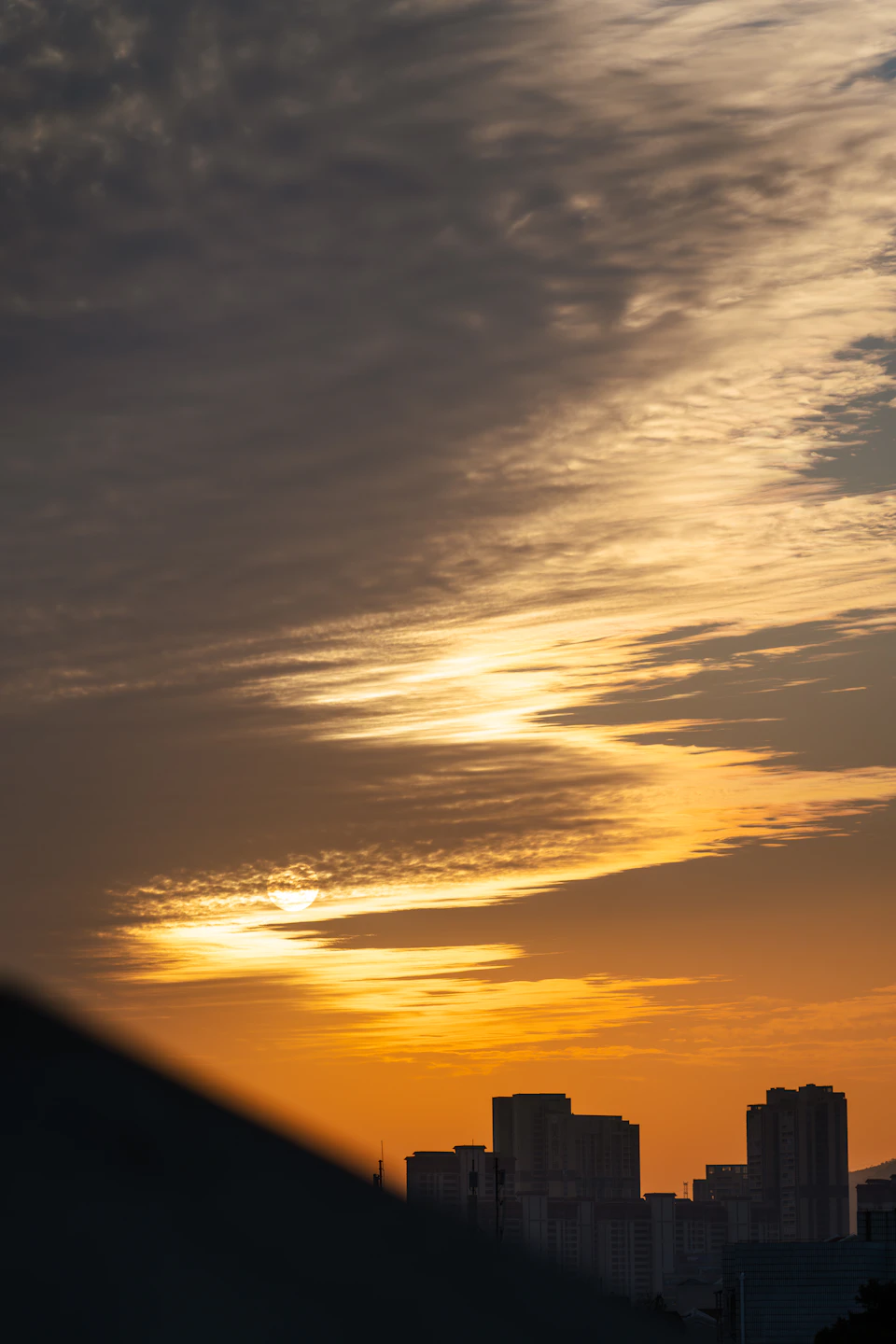 City skyline at sunset with sun setting behind buildings and casting long shadows