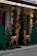 An outdoor holiday display features decorative reindeer figures and Christmas trees adorned with red baubles and lights. The setting includes a building with signage above and cobblestone pavement below, giving it a festive and welcoming atmosphere.