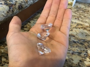 Hands presenting a certificate of authenticity alongside a set of vibrant precious stones on a wooden table.