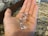 A hand holds three transparent, faceted stones resembling diamonds. The background features a granite countertop with a speckled pattern.