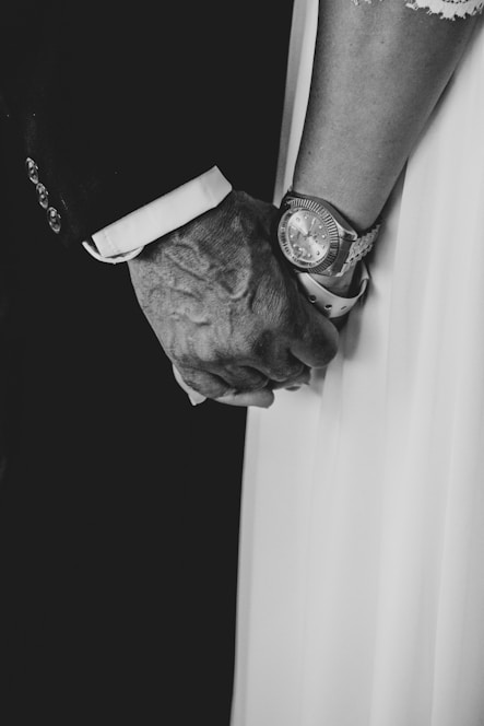 An elderly hand gently holding the SilentCare wristband glowing softly in medical blue and coral hues.