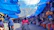 A woman inspecting a large blue tarpaulin covering a market stall in Africa.