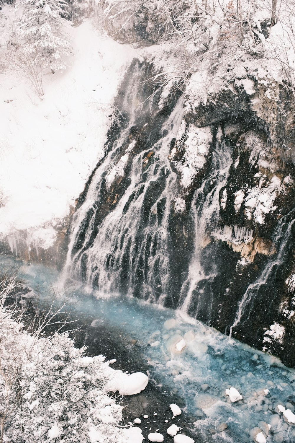 a waterfall in the middle of a snowy forest