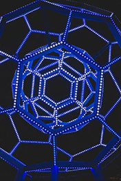 Abstract wireframe structure illuminated by electric blue lines on a deep charcoal background.