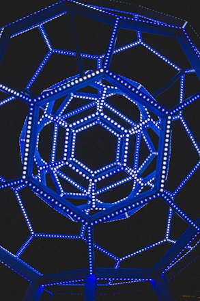 Abstract wireframe structure illuminated by electric blue lines on a deep charcoal background.